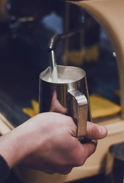 Hand with a pitcher. Whipping milk. Barista