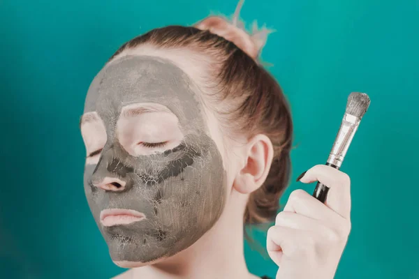 Girl in a clay mask. Cosmetology procedure