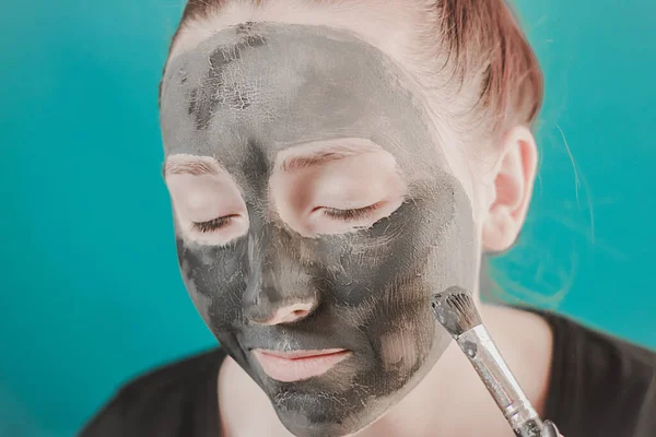 Girl in a clay mask. Cosmetology procedure