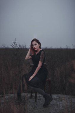  Kırmızı dudaklı güzel kız tarlada bir sandalyede oturuyor.