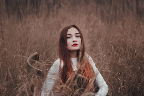 Portrait of a beautiful redhead girl in a field