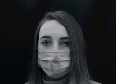 Siyah arka planda mavi tıbbi maskeli genç bir kadın. Coronavirus koruması