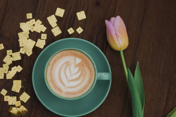 Koffie Een Groene Beker Met Een Roze Tulp Een Houten — Stockfoto