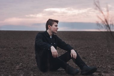 Sahadaki siyahlı genç adam. Pembe günbatımı. Ciddi iş adamı.