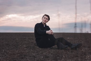 Sahadaki siyahlı genç adam. Pembe günbatımı. Ciddi iş adamı.