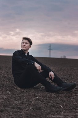 Sahadaki siyahlı genç adam. Pembe günbatımı. Ciddi iş adamı.