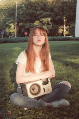 Güzel bir kız elinde bir sütunla çimlerin üzerinde oturuyor. Klasik stil