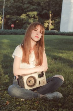 Güzel bir kız elinde bir sütunla çimlerin üzerinde oturuyor. Klasik stil