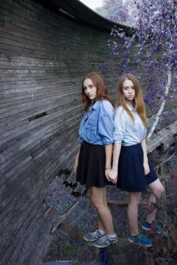 İki kız arkadaş doğada el ele tutuşur. Mavi yaprak