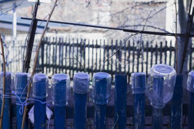 Teneke kutular mavi bir çite tutunur.