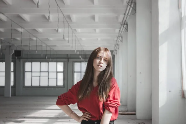 Confident woman in a white loft. Portrait of a beautiful girl in a white room with large windows