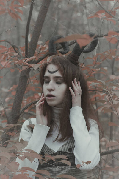Gloomy girl with horns in the forest. Halloween image