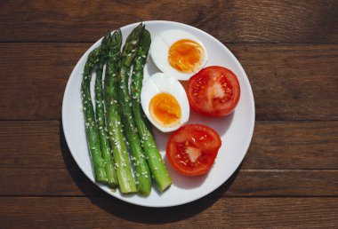 Kuşkonmaz, yumurta ve domatesli kahvaltı. Sebzeler. Ahşap arka planda yemek.