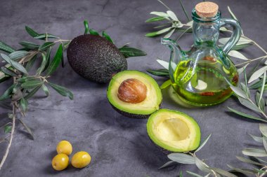Taze yeşil avokado ve siyah arka planda zeytin yağı..