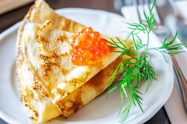 Kırmızı havyarlı fırında sıcak krep ve bir dal dereotu.