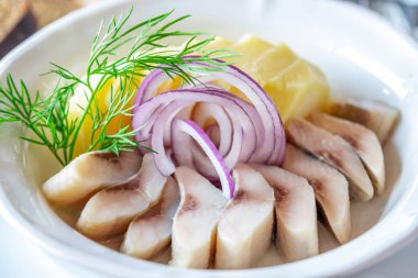 Bir dilim tuzlanmış ringa balığı ve haşlanmış patates, dekore edilmiş. 