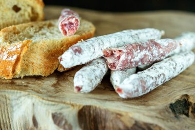 İnce İspanyol sosis parmakları ve tahtada beyaz ekmek.