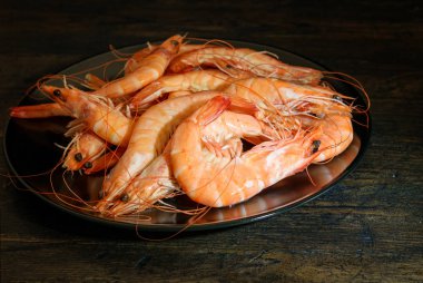 Büyük karidesler kara tabakta ve ahşap doğal taşralılarda.