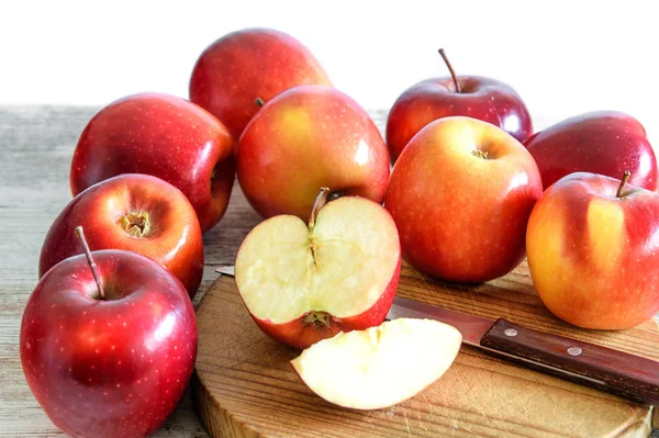 Manzanas rojas frescas enteras y rebanadas en el tablero de la cocina de madera un — Foto de Stock