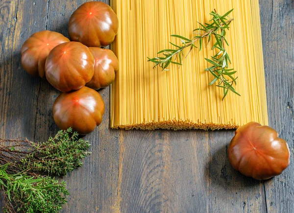 Lange ungekochte Spaghetti mit frischen Tomaten, Rosmarin auf dem Woo — Stockfoto