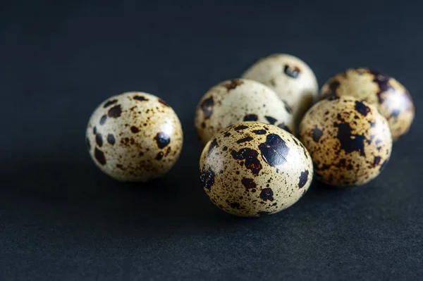 Quail spotted eggs on the black background closeup. Black texture, dark mode. Healthy food concept.