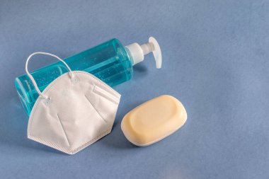 Bir şişe sıvı jel dezenfektanı, bir kalıp sabun ve virüs, grip ve enfeksiyonları korumak için tıbbi maske. Hijyen ürünleri, sağlık hizmetleri kavramı. 