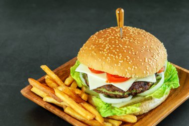 Ispanak ve sebze pirzolalı vejetaryen burger. Koyu arkaplanda, ahşap eko tabakta patates kızartması. Üst Manzara. Vejetaryenler için lezzetli fast food.. 