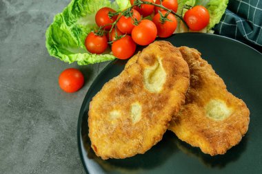 Doğal zeytinyağıyla kızartılmış sıcak navajo ekmeği, kirazlı domates ve siyah tabakta biraz yeşil. Geleneksel Hint Navajo ekmek tarifi. 