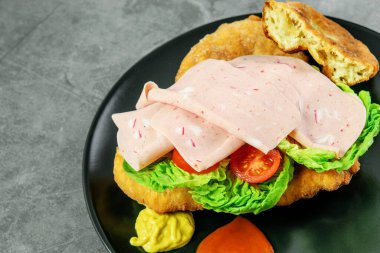 Navajo flatbread taco, jambon, sebze ve sosla kaplanmış siyah tabak. Amerikan Hindistanlı fast food Navajo taco. 