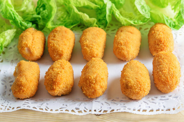 Croquettes and fresh green lettuce on the white plate. Light low weight fast food. 