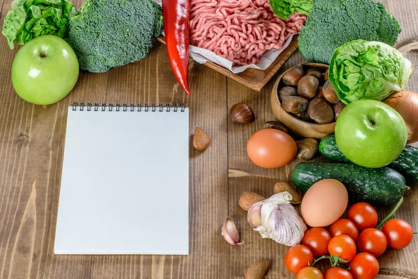 Ketogenik diyet yemek geçmişi ve notlar için kağıt bir liste. Ahşap arka planda taze sebze ve meyve. Sağlıklı keto diyet ürünleri, sağlıklı yaşam konsepti.
