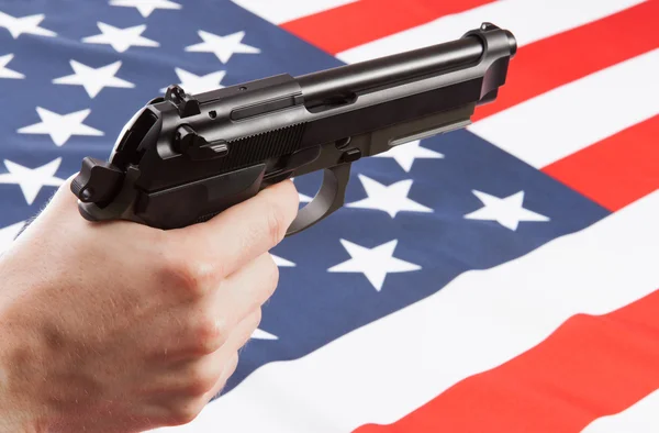 Пистолет в руке с флагом на фоне - Соединенные Штаты Америки — стоковое фото