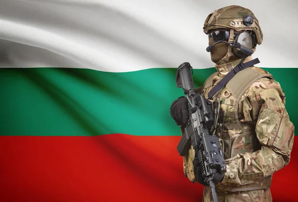 Żołnierz w kask trzyma karabin maszynowy z flagi na tle serii - Bułgaria — Zdjęcie stockowe