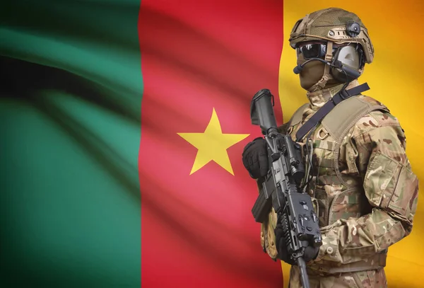 Żołnierz w kask trzyma karabin maszynowy z flagi na tle serii - Kamerun — Zdjęcie stockowe