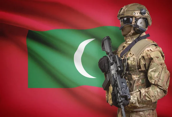 Солдат в шлеме, держа пистолет с флагом на фоне серии - Мальдивы — стоковое фото