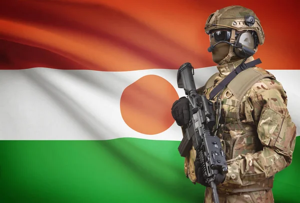 Soldier in helmet holding machine gun with flag on background series - Niger — Stok Foto