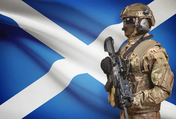 Soldier in helmet holding machine gun with flag on background series - Scotland — Stock Photo, Image