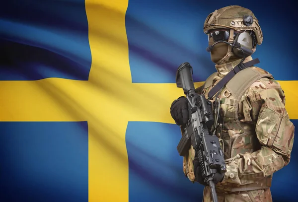 Żołnierz w kask trzyma karabin maszynowy z flagi na tle serii - Szwecja — Zdjęcie stockowe