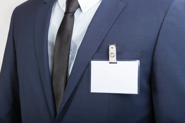 Hombre de negocios con una tarjeta de identificación en etiqueta o nombre en blanco durante una exposición o una conferencia —  Fotos de Stock
