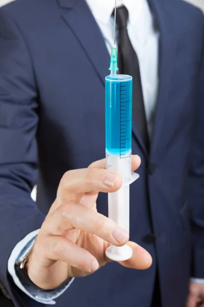 Businessman holding big syringe in hand — Stock Photo, Image