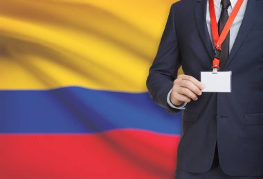 Arka plan - Kolombiya Ulusal bayrakla bir ip üzerinde yaka kartı tutan işadamı