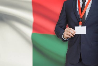 Arka plan - Madagaskar üzerinde ulusal bayrakla bir ip üzerinde yaka kartı tutan işadamı