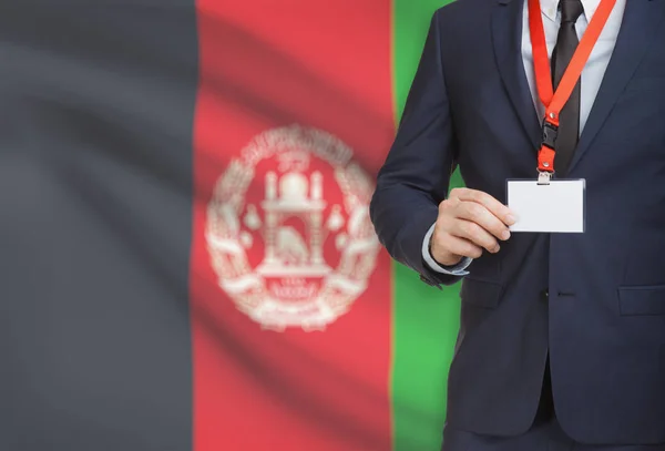 Biznesmen gospodarstwa karta identyfikator na smyczy z flagi narodowej na tle - Afganistan — Zdjęcie stockowe