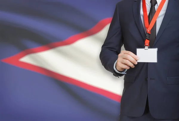 Businessman holding name card badge on a lanyard with a national flag on background - American Samoa — Stock Photo, Image