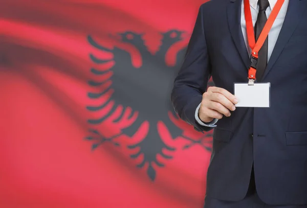 Businessman holding name card badge on a lanyard with a national flag on background - Albania — Stock Photo, Image