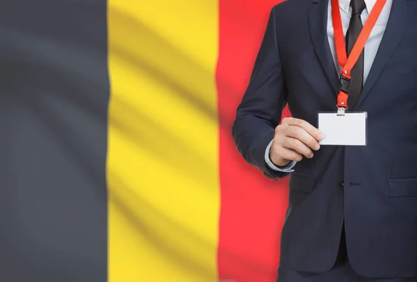 Бизнесмен Холдинг карты бэдж на ремень с национальным флагом на фоне - Бельгия — стоковое фото