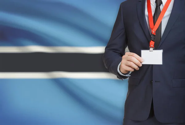 Empresario sosteniendo credencial tarjeta en una cuerda con una bandera nacional de fondo - Botswana —  Fotos de Stock