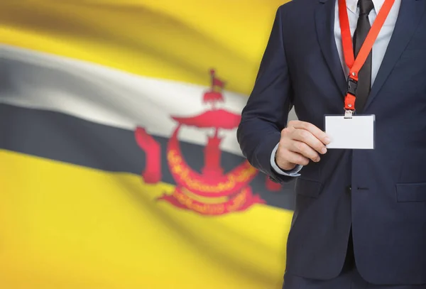 Empresário, segurando o distintivo de cartão nome em uma corda com uma bandeira nacional no plano de fundo - Brunei — Fotografia de Stock