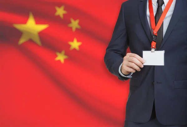 Empresário, segurando o distintivo de cartão nome em uma corda com uma bandeira nacional no plano de fundo - China — Fotografia de Stock