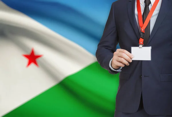 Empresario sosteniendo credencial tarjeta en una cuerda con una bandera nacional de fondo - Djibouti — Foto de Stock